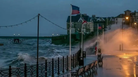 The seaside resort of Clevedon with high waves crashing over the promenade railings onto the road