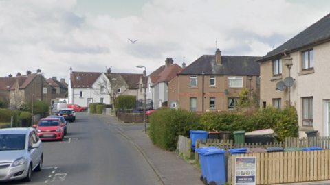 Several cars are parked on Cardross Avenue outside terraced homes