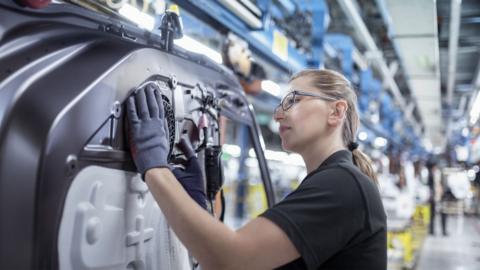 A woman working on manufacturing a car door.