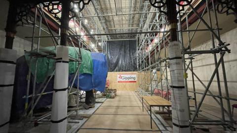 A photo inside Ipswich Museum's central Victorian Natural History Gallery. Scaffolding is erected across the room with a mammoth sculpture placed at one side underneath plastic wraps.