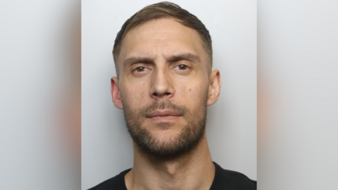 Daniel New has short brown hair and brown stubble on his face in his mug shot.