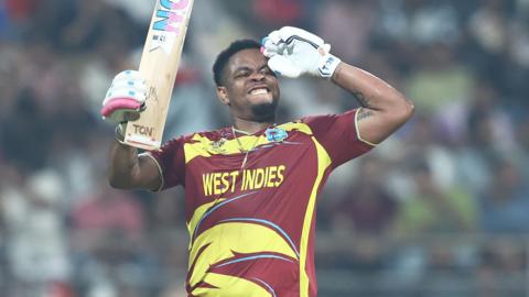 Shimron Hetmyer celebrates reaching a fifty by saluting with his left arm, and holding the blade of his bat with his right hand
