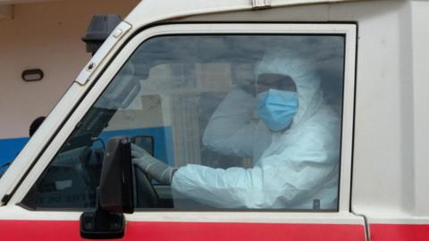 A doctor wearing personal protective equipment sits in an ambulance at the Ebola Virus Disease Treatment Center at the Bunia General Reference Hospital. 