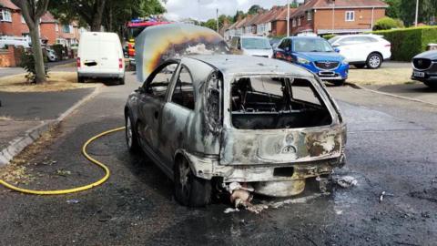 A destroyed white Vauxhall Corsa