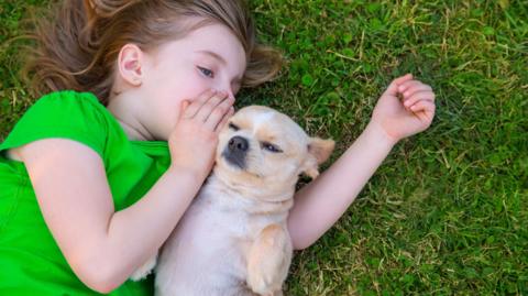 girl whispering in dog's ear. 