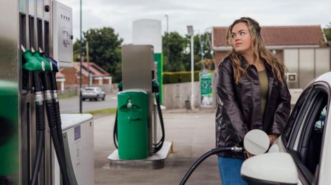 Woman filling her car at a petrol station in the North East of England
