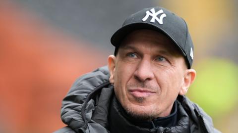 Gerhard Struber wearing a black cap while walking on the pitch during a match