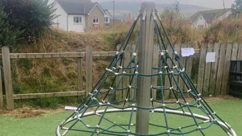 A netter cone shape climbing frame held up by a metal pole.