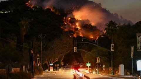 Fires burn on the hillside - with LA traffic driving underneath