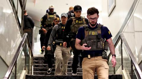 FBI officers walk down a set of stairs wearing tactical gear during the shooting
