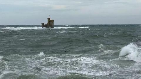Choppy seas with waves breaking around the Tower of Refuge in Douglas Bay.