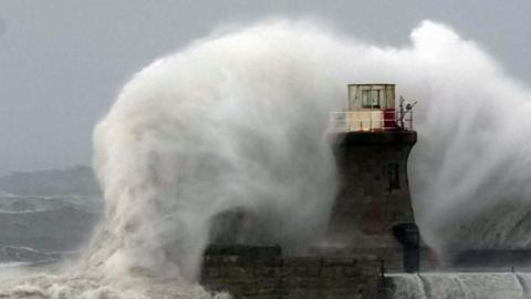Large wave crashing against a lighthouse.