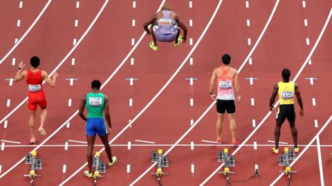 Noah Lyles jumps in the air on the start line for the 100m heats at the World Athletics Championships in Tokyo