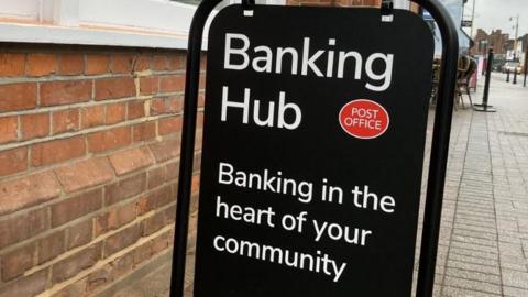 A sign that reads: BANKING HUB POST OFFICE BANKING IN THE HEART OF THE COMMUNITY