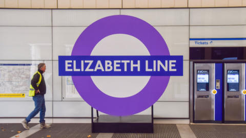 Man walks past an Elizabeth line sign on a station platform