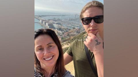 Selfie of Alison and her teenage son, who is wearing sunglasses, on a sunny day with a view of Alicante and the sea behind them