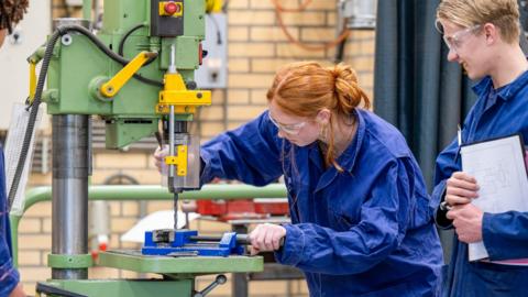 Two young people operating machinery during an apprenticeship