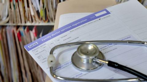 A photo of a GP registration form and a stethoscope.