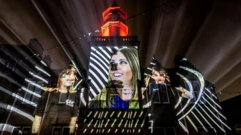 The projection shows young people smiling. The light also has a stripey effect.