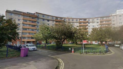 A block of curved flats which are mainly white with orange balconies.