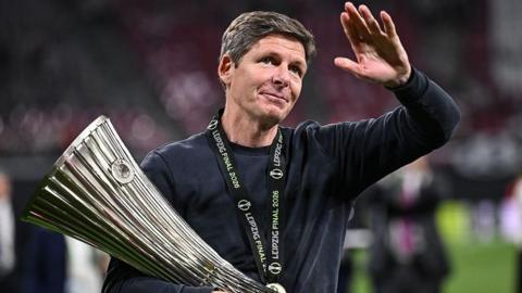 Oliver Glasner waves to the crowd while holding the Europa Conference League trophy