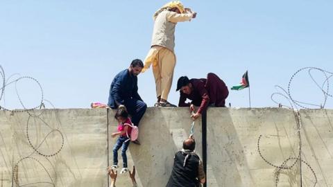 Afghans scaling a wall to access Kabul airport during the evacuation in 2021