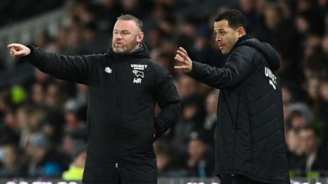 Wayne Rooney and Liam Rosenior on the touchline wearing black Derby County team coats