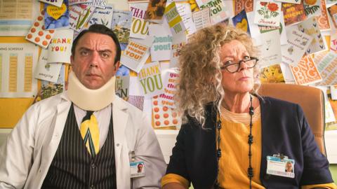 a man wearing a sponge neck brace is sitting next to a woman with curly hair and glasses, both looking confused 
