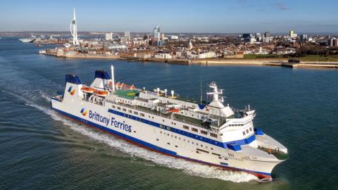 Barfleur, with the Brittany Ferries logo across its starboard-side, under power with the island behind it