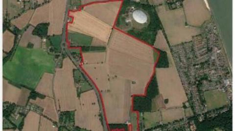 An aerial map of the site showing green fields, farmland and residential areas with the site earmarked for development outlined with a red border