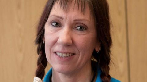 A close-up photograph shows Deborah Monk with her hair in plaits and wearing the charity's blue top.