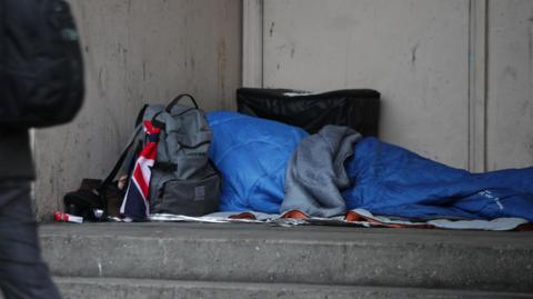 A homeless person sleeping rough in a doorway.