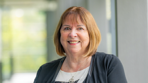 A woman with a bob smiling at the camera with a blurred background.