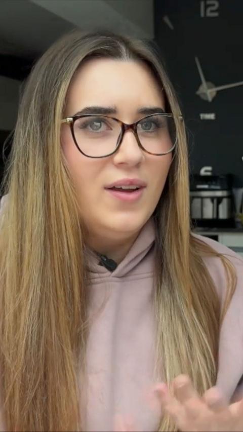 Close up of young woman with light brown hair glasses and a pink top