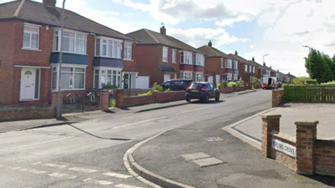 A street corner with a sign reading 'Kipling Grove' in the bottom left of the picture. A car is parked on the curb near a row of detached houses.