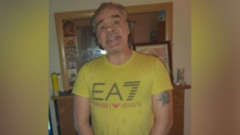 Man with light hair and beard posing for camera wearing a yellow t-shirt 