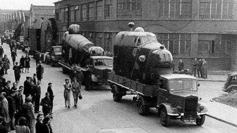 Photograph of aeroplane cockpits being transported on the back of lorries. The picture was taken at the Fairey Aviation factory at Heaton Chapel in WW2.