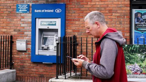 Person walking past a Bank of Ireland cash machine, which had been hit by technical glitches