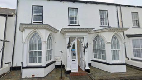 Former Guest House at 19 The Green, Seaton Carew. The white building has gothic shaped windows and sash windows one the second floor. 