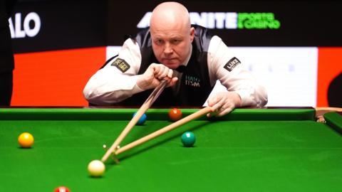 John Higgins plays a shot