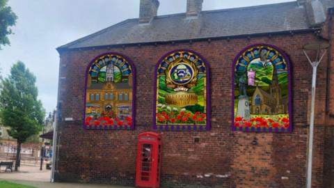 A mock of how a proposed mural will appear on a wall in Ossett. It features three archway 'windows' each depicting images of the town against the red brick of the building