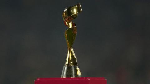 The picture shows the FIFA Women's World Cup at the final in of the 2023 tournament/ The trophy is gold with swirls going round a ball 