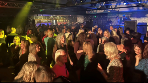 A crowded dance floor with people disco dancing 