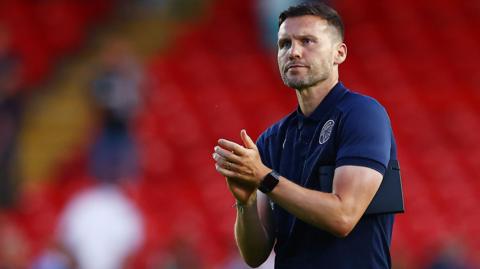 Walsall boss Mat Sadler claps the fans after a match