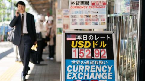 Pedestrians walk past currency exchange stores.