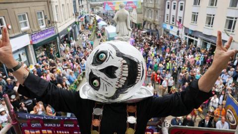 A person with a giant white ball on their head, with eyes and skeletal features drawn on it