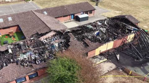 An aerial image of a fire-wrecked single storey building. The roof has been destroyed in parts and the inside of the building blackened by fire and smoke.