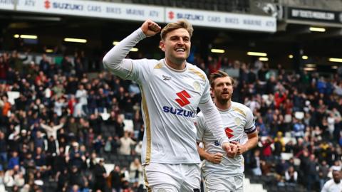 Laurence Macguire runs with his fist in the air after scoring a goal