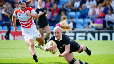 New Zealand's Jorja Miller scores her sides second try during the Women's Rugby World Cup 2025 Pool C match at Sandy Park, Exeter, against Japan. Miller is wearing an All Black kit. A Japanese player is chasing her in a red and white kit.
