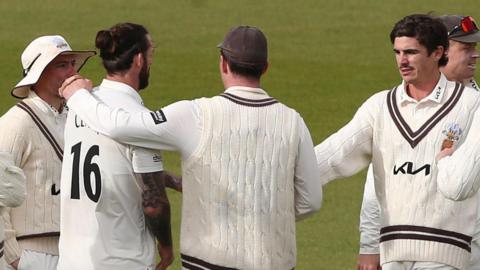Surrey players congratulate Jordan Clark (16) after taking a wicket